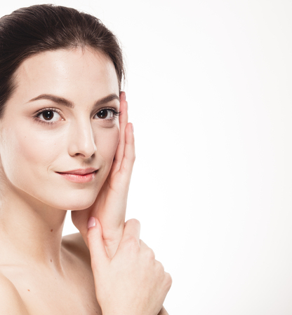 Beauty Woman face Portrait. Beautiful model Girl with Perfect Fresh Clean Skin. Brunette female looking at camera and smiling. Youth and Skin Care Concept. Isolated on a white backgroundの写真素材