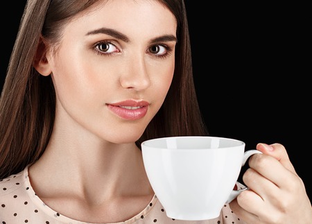 Young beautiful white woman with white cup. Isolated on black background. Studio shot.の写真素材