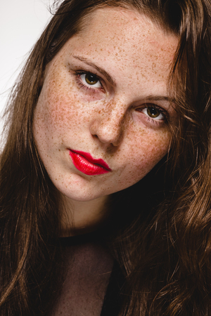 Young beautiful freckles woman face portrait with healthy skin. Studio shot. Isolated on white.の写真素材