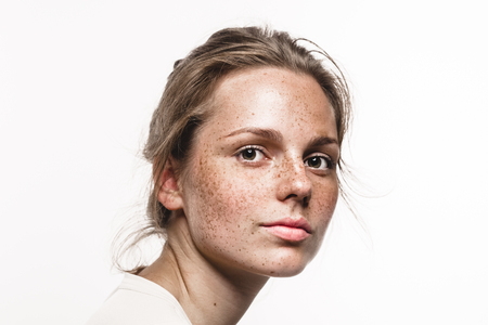 Young beautiful freckles woman face portrait with healthy skin. Studio shot. Isolated on white.の写真素材