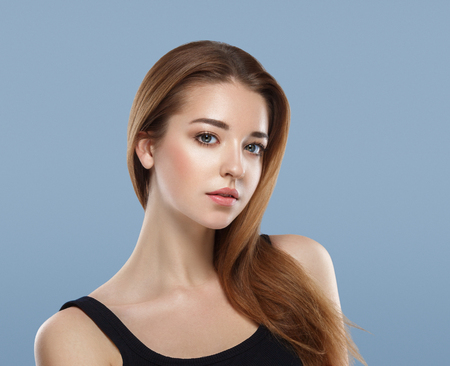 Beautiful woman face close up portrait young studio on blue. Studio shot.の写真素材