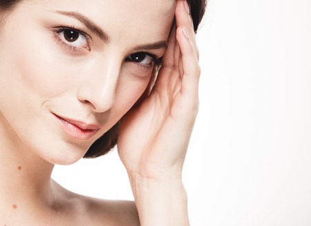 Beauty Woman face Portrait. Beautiful model Girl with Perfect Fresh Clean Skin. Brunette female looking at camera and smiling. Youth and Skin Care Concept. Isolated on a white backgroundの写真素材