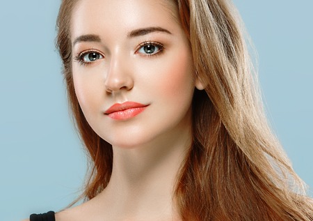 Beautiful woman portrait face on blue background. Studio.の写真素材