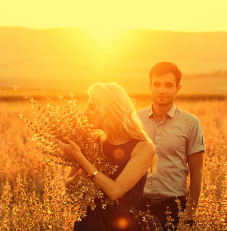 Beautiful and young couple in love together on summer field. Uptdoor shot.の写真素材