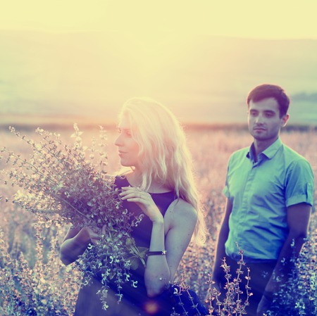 Beautiful and young couple in love together on summer field. Uptdoor shot.の写真素材