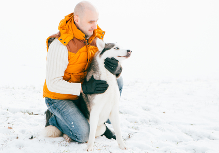 Man walking with dog winter time with snow in forest Huskies friendship. Outdoor.の写真素材