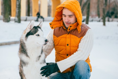 Man walking with dog winter time with snow in forest Huskies friendship. Studio.の写真素材
