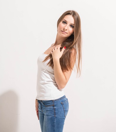 young beautiful woman portrait near white wall in jeans.の写真素材