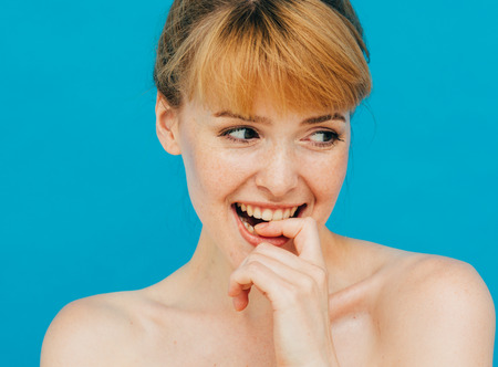 Beauty Woman face Portrait. Beautiful model Girl with Perfect Fresh Clean Skin color lips purple red. Healthy teeth smile Youth and Skin Care Concept over blue backgroundの写真素材