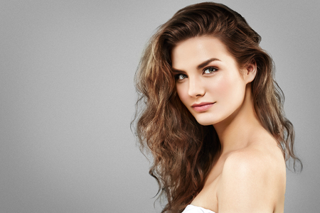 Beautiful woman face close up portrait young curly hair studio on gray. Studio shotの写真素材