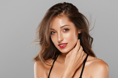 Beautiful Woman Skin Tanned Red Lips Healthy Beauty Skin Smile. Spa Beautiful Model Girl Cute Face over gray background.の写真素材