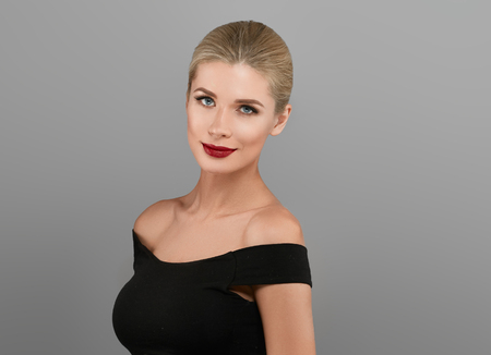Blonde beautiful woman model over gray background. Woman nail manicure lipstick same color beauty portrait beautiful careの写真素材