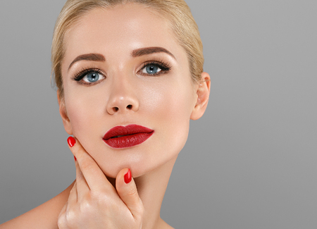 Young beautiful woman with red lips and nails manicure blonde hair girl. Studio shot.の写真素材