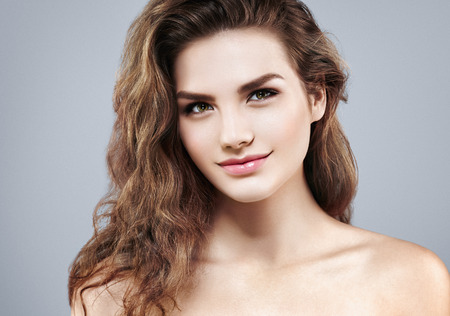 Beautiful woman face close up portrait young curly hair studio on gray. Studio shotの写真素材