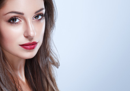 Beautiful Woman Skin Tanned Red Lips Healthy Beauty Skin Smile. Spa Beautiful Model Girl Cute Face over color background.の写真素材