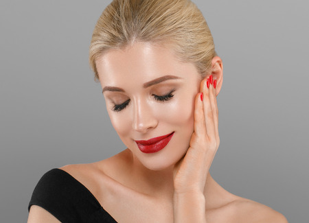 Blonde beautiful woman model over gray background. Woman nail manicure lipstick same color beauty portrait beautiful careの写真素材