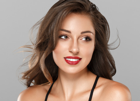 Beautiful Woman Skin Tanned Red Lips Healthy Beauty Skin Smile. Spa Beautiful Model Girl Cute Face over gray background.の写真素材