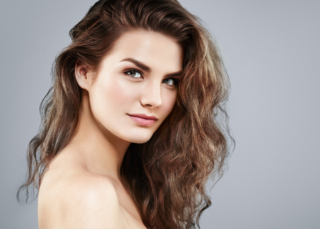 Beautiful woman face close up portrait young curly hair studio on gray. Studio shotの写真素材