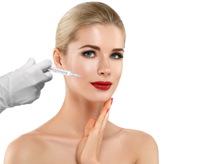 People, cosmetology, plastic surgery and beauty concept - beautiful young woman face and hand in glove with syringe making injectionの写真素材