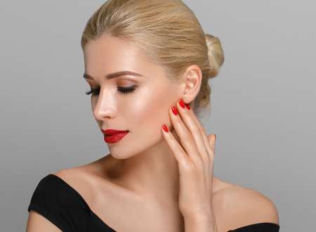 Blonde beautiful woman model over gray background. Woman nail manicure lipstick same color beauty portrait beautiful careの写真素材