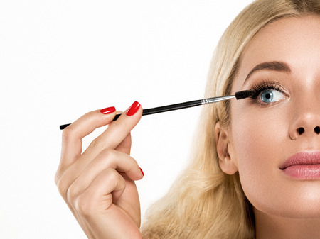 Mascara brush. Beautiful Blonde Girl Portrait with healthy Hair and Red Lips.Clear Fresh Skin.Smiling Girl Isolated on a White Background.Skincare.Spa.Beauty Modelの写真素材