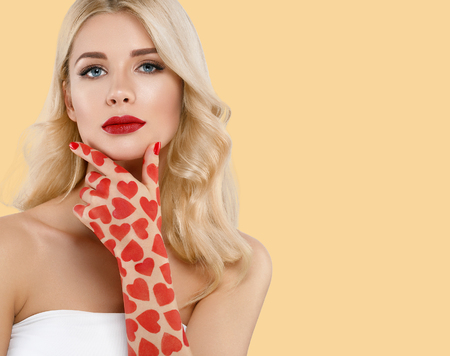 Beautiful woman Valentines Day Hearts concept. Blond Woman red lips over yellow background. Studio shot.の写真素材