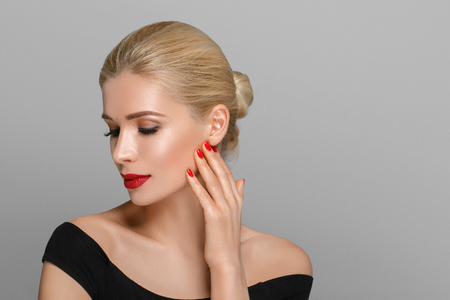 Blonde beautiful woman model over gray background. Woman nail manicure lipstick same color beauty portrait beautiful careの写真素材