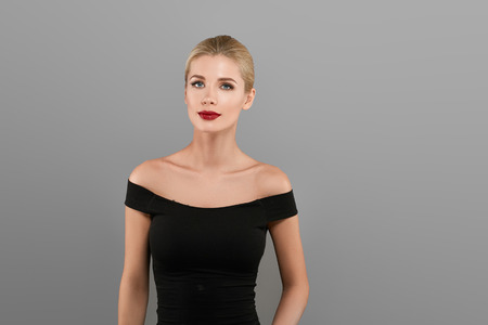 Blonde beautiful woman model over gray background. Woman nail manicure lipstick same color beauty portrait beautiful careの写真素材