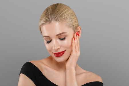 Blonde beautiful woman model over gray background. Woman nail manicure lipstick same color beauty portrait beautiful careの写真素材