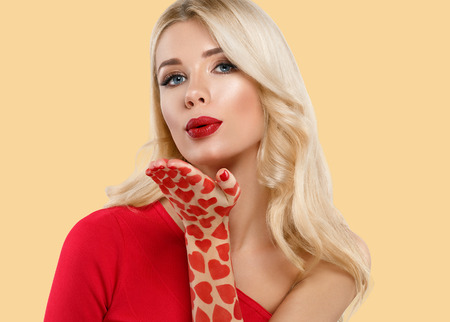 Beautiful woman Valentines Day Hearts concept. Blond Woman red lips over yellow background. Studio shot.の写真素材