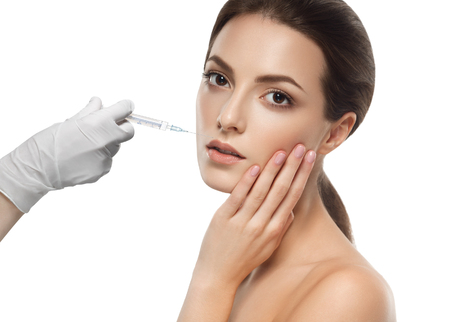 People, cosmetology, plastic surgery and beauty concept - beautiful young woman face and hand in glove with syringe making injectionの写真素材