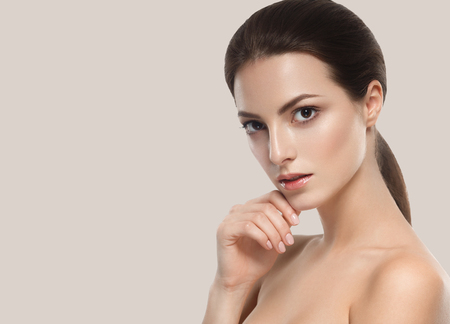 Beautiful woman skincare portrait with hand over beige background. Studio shot.の写真素材