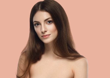 Beautiful Woman Girl brunette hair hands touching skin on summer pink trendy color background. Studio shot.の写真素材