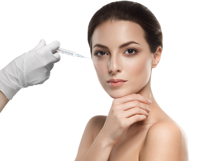 People, cosmetology, plastic surgery and beauty concept - beautiful young woman face and hand in glove with syringe making injectionの写真素材
