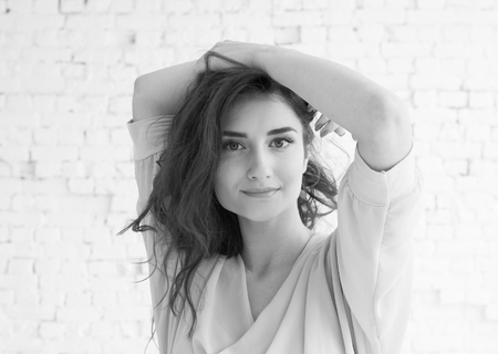 Young beautiful woman day light natural face portrait over brick wall black and white. Indoor shot.の写真素材