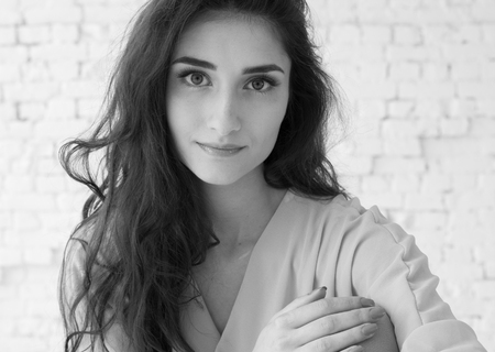 Young beautiful woman day light natural face portrait over brick wall black and white. Indoor shot.の写真素材