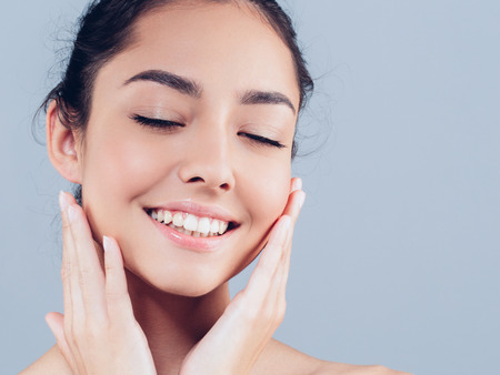 Beautiful Woman Face with hands Portrait Beauty Skin Care Concept. Fashion Beauty Model isolated on gray backgroundの写真素材