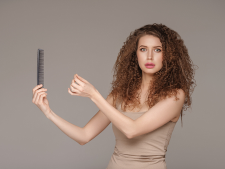 Woman with hair long brush problem. Studio shot.の写真素材