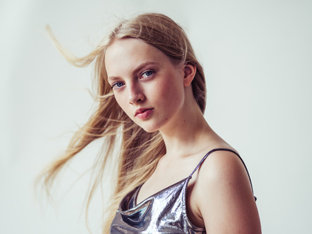 Beautiful blonde woman girl with long blond hair smooth and beauty in silver wear. Studio shot.の写真素材
