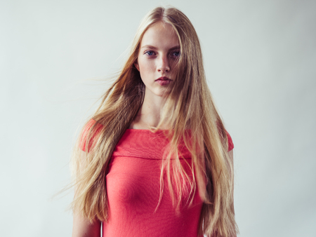 Beautiful long blonde hair woman in red dress natural over white background. Studio shot.の写真素材