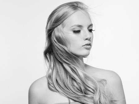 Blonde long hair woman beauty portrait with beautiful hairstyle isolated on white monochromeの写真素材