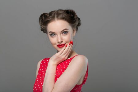 Pin up woman portrait. Beautiful retro female in polka dot dress with red lips. Studio shot.の写真素材