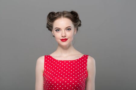 Pin up woman portrait. Beautiful retro female in polka dot dress with red lips. Studio shot.の写真素材