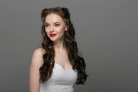 Pin up woman portrait. Beautiful retro female in polka dot dress with red lips. Studio shot.の写真素材