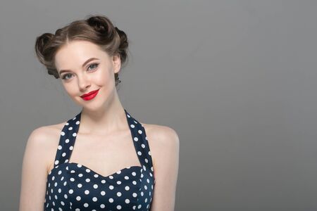 Pin up woman portrait. Beautiful retro female in polka dot dress with red lips. Studio shot.の写真素材