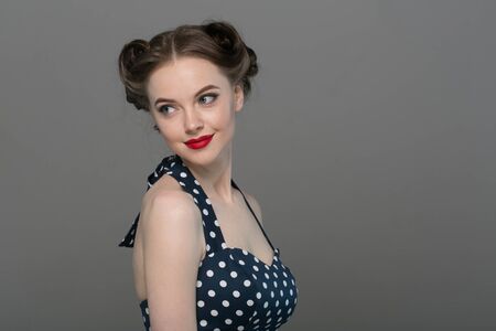 Pin up woman portrait. Beautiful retro female in polka dot dress with red lips. Studio shot.の写真素材