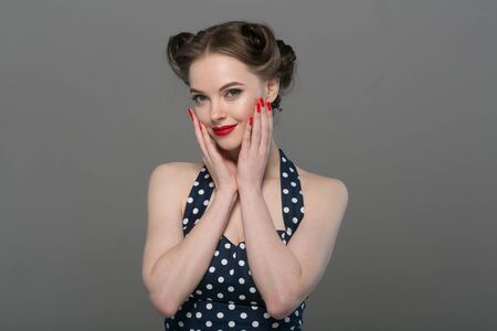 Pin up woman portrait. Beautiful retro female in polka dot dress with red lips. Studio shot.の写真素材