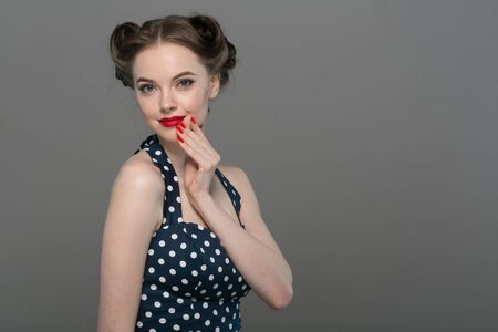 Pin up woman portrait. Beautiful retro female in polka dot dress with red lips. Studio shot.の写真素材