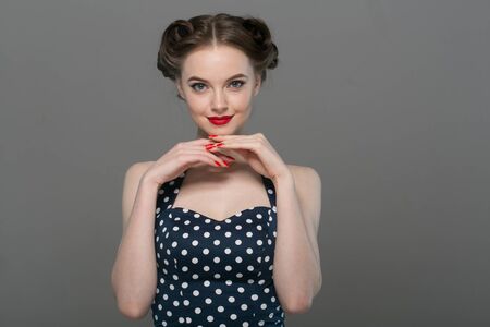 Pin up woman portrait. Beautiful retro female in polka dot dress with red lips. Studio shot.の写真素材