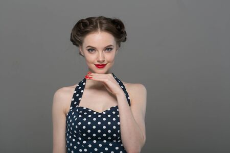 Pin up woman portrait. Beautiful retro female in polka dot dress with red lips. Studio shot.の写真素材